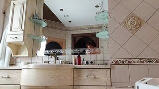 A Charming Woman Is Preening in the Bathroom in Front of a Mirror